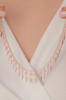 Çok güzel kolyeler ve bakımlı tırnaklar sunar. Parlak kolyesi olan güzel genç bir kadın..