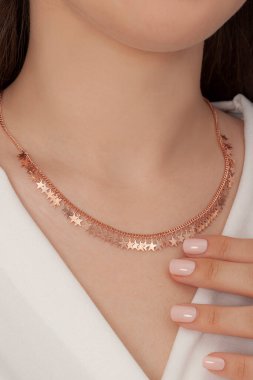 Tırnakları bakımlı olan bayan, çok güzel kolyeler veriyor. Gümüş, elmas, altın kolyeler.