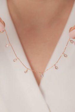 Çok güzel kolyeler ve bakımlı tırnaklar sunar. Parlak kolyesi olan güzel genç bir kadın..