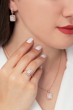 Güzelce döşenmiş tırnakları olan güzel bir mücevher seti sunuyor. Kolye, küpe ve yüzük gümüş, elmas, altın.