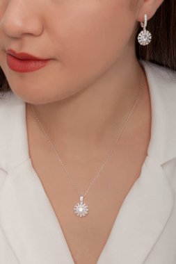 Beyaz elbiseli bayanın taktığı yuvarlak taşlı elmas takılar..