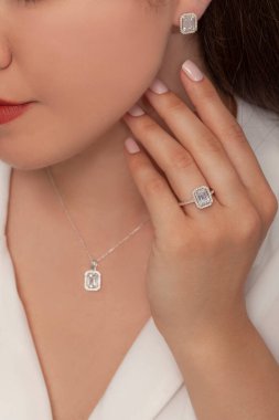 Güzelce döşenmiş tırnakları olan güzel bir mücevher seti sunuyor. Kolye, küpe ve yüzük gümüş, elmas, altın.