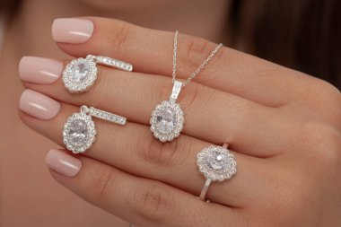 Çok güzel kolyeler ve bakımlı tırnaklar sunar. Parlak kolyesi olan güzel genç bir kadın..