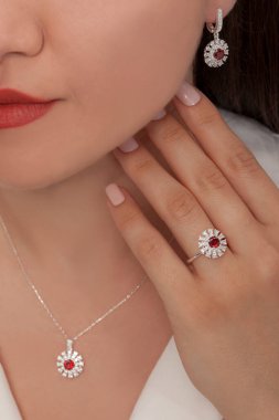 Güzelce döşenmiş tırnakları olan güzel bir mücevher seti sunuyor. Kolye, küpe ve yüzük gümüş, elmas, altın.