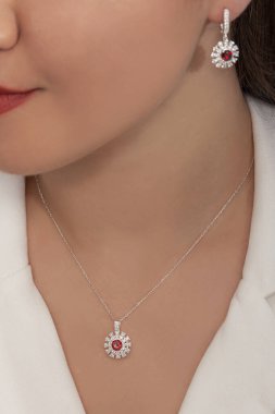 Beyaz elbiseli bayanın taktığı yuvarlak taşlı elmas takılar..