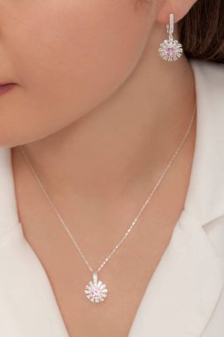 Beyaz elbiseli bayanın taktığı yuvarlak taşlı elmas takılar..