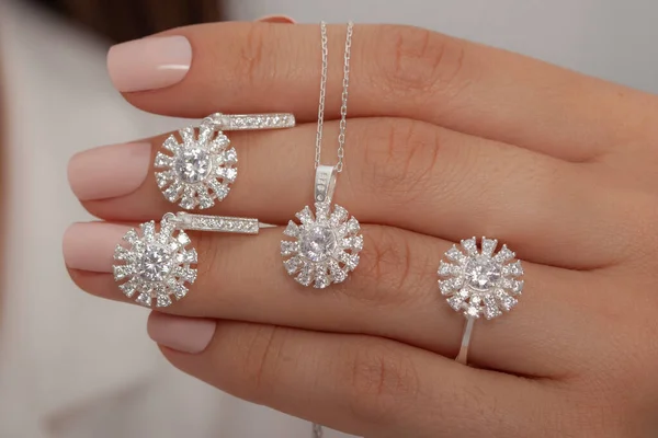 diamond jewelry set in female hands in white outfit. Jewelry image for e-commerce.