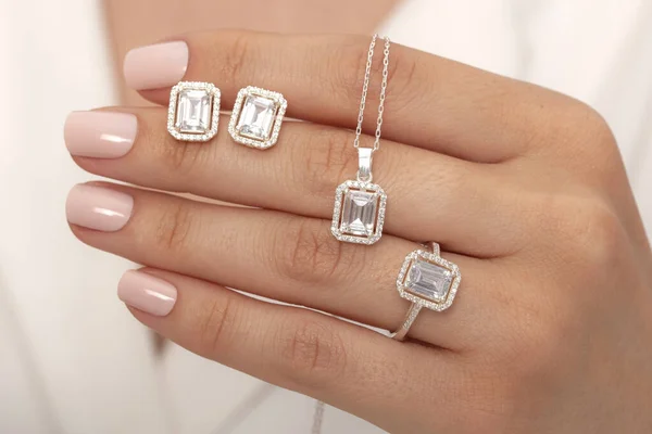 diamond jewelry set in female hands in white outfit. Jewelry image for e-commerce.