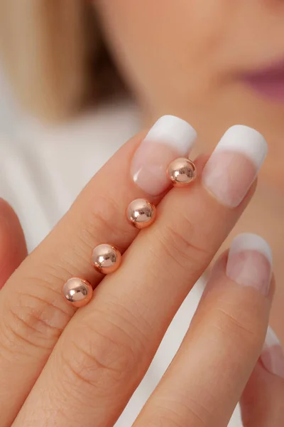 Woman showing silver earrings on her manicured well-groomed hands. Earring image for online sales.