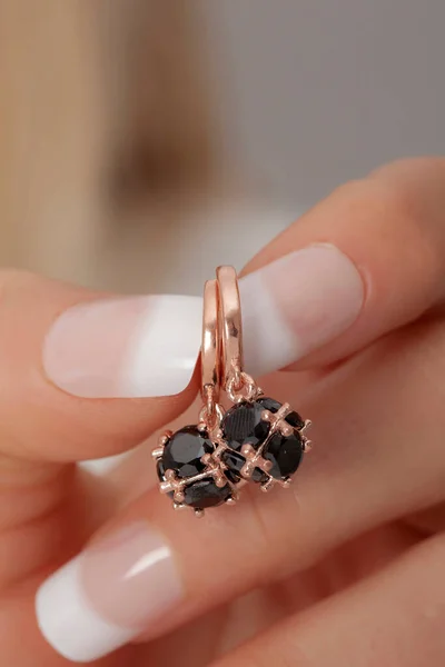 Woman showing silver earrings on her manicured well-groomed hands. Earring image for online sales.