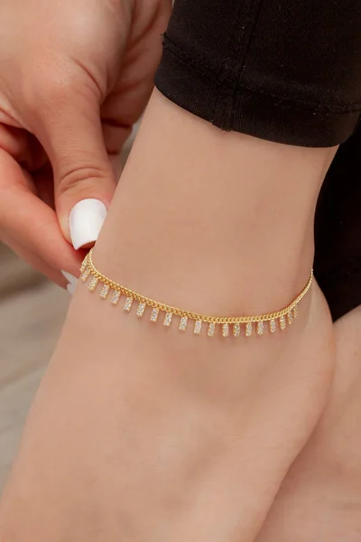 On her thin ankle, on the girl\'s foot with white nail polish, silver anklets with colored and stones, anklet detail. Online sale anklet image