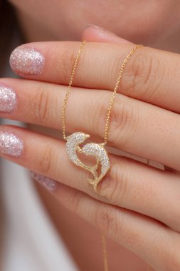 Elinde parlak ojeli bir kızın gümüş zarif kolyesi.