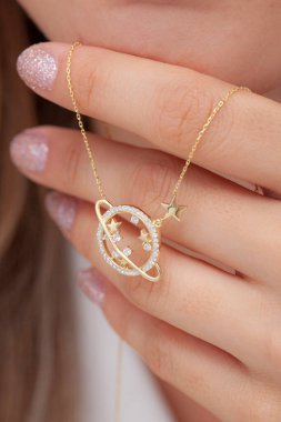 Elinde parlak ojeli bir kızın gümüş zarif kolyesi.