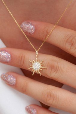 Elinde parlak ojeli bir kızın gümüş zarif kolyesi.