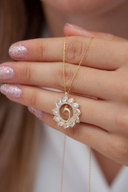 Elinde parlak ojeli bir kızın gümüş zarif kolyesi.