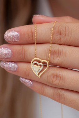 Elinde parlak ojeli bir kızın gümüş zarif kolyesi.