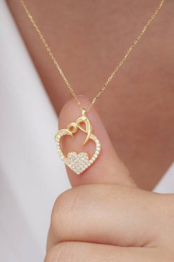 Elinde parlak ojeli bir kızın gümüş zarif kolyesi.