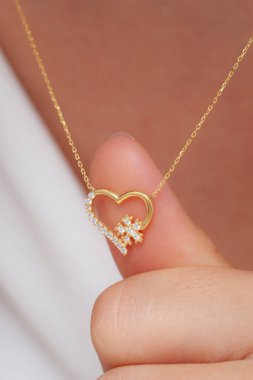 Elinde parlak ojeli bir kızın gümüş zarif kolyesi.