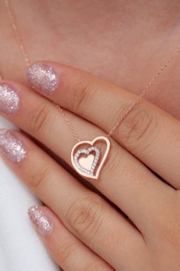 Elinde parlak ojeli bir kızın gümüş zarif kolyesi.