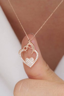 Elinde parlak ojeli bir kızın gümüş zarif kolyesi.