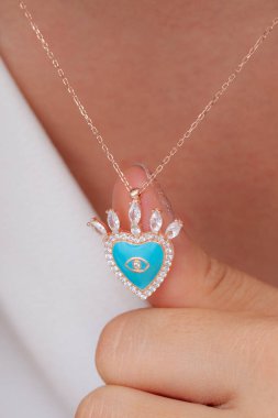 Elinde parlak ojeli bir kızın gümüş zarif kolyesi.