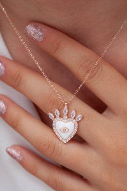 Elinde parlak ojeli bir kızın gümüş zarif kolyesi.