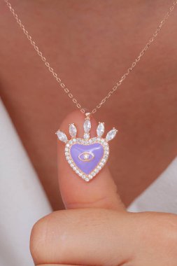 Elinde parlak ojeli bir kızın gümüş zarif kolyesi.