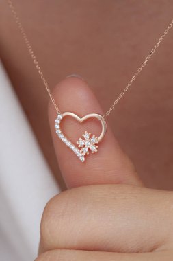 Elinde parlak ojeli bir kızın gümüş zarif kolyesi.