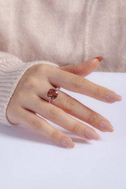 Pembe kazaklı, bakımlı elleri olan kızın parmağında pırlanta bir yüzük. E-ticaret için halka resmi.