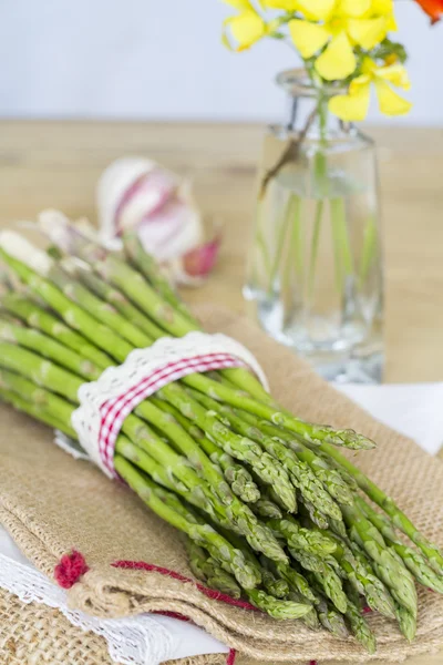 Bunch of green asparagus, tied with ribbon of red and white — Stock Photo, Image