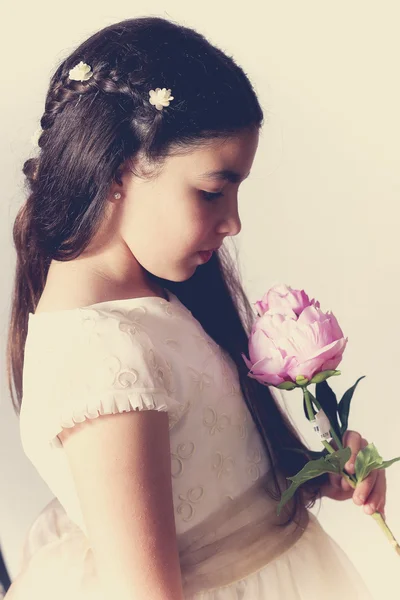 Doce menina com vestido de comunhão segurando uma peônia — Fotografia de Stock