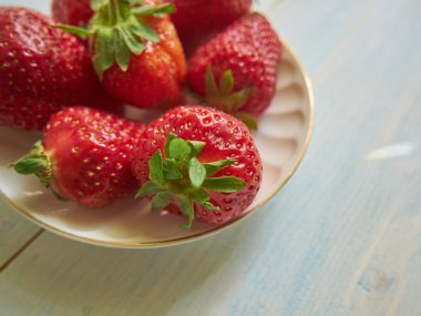 çilek beyaz bir tabak içinde. Ahşap arka plan üzerinde çilek plakadır
