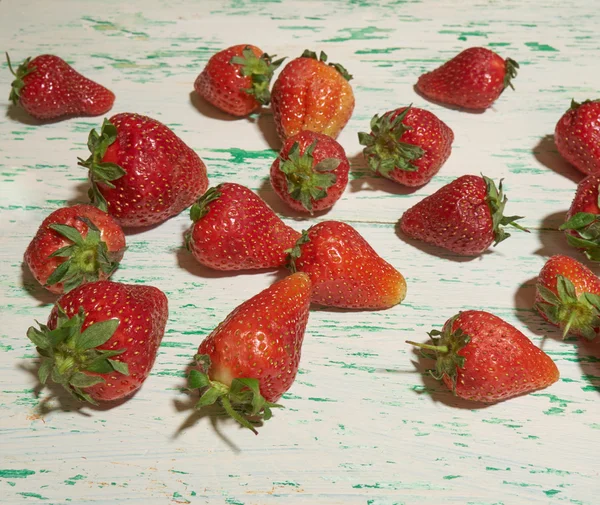 Scattering of strawberries lying old wooden background — Stock Photo, Image