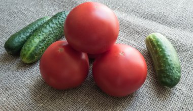 Yeşil salatalık ve çuval bezi üzerinde kırmızı domates