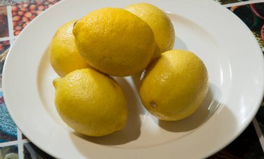 Yakın plan: beyaz bir tabakta beş limon.