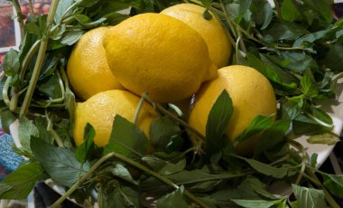 Yakın plan: Sarı kesme tahtasındaki beş limon ve naneli şeker.