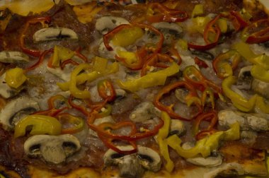 Yakın plan: mantarlı, salamlı, kırmızı ve sarı biberli ev yapımı pizza.