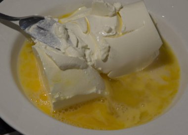 Yakın plan: beyaz bir tabakta kaşık kullanarak ekşi kremayla karıştırılmış çırpılmış yumurta