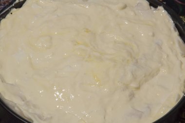 Yakın plan: Ekşi kremayla kaplı banitsa pişirmeye hazır metal bir formda.