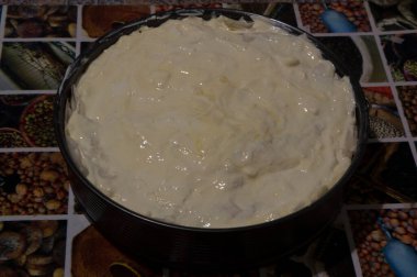 Yakın plan: Ekşi kremayla kaplı banitsa pişirmeye hazır metal bir formda.