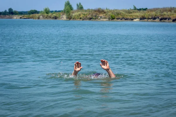 Hands of a drowning man above water in need of help.