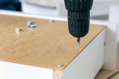 Mobilya montajı, marangoz tornavidayla kendi kendine tıkırdayan bir vidayı çekmeceye sokuyor..