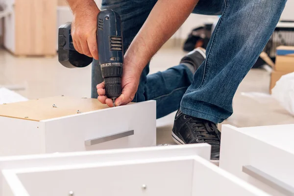 Mobilya montajı, marangoz tornavidayla kendi kendine tıkırdayan bir vidayı çekmeceye sokuyor..