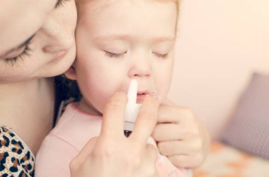 Anne küçük bir çocuğun burnuna damlıyor..