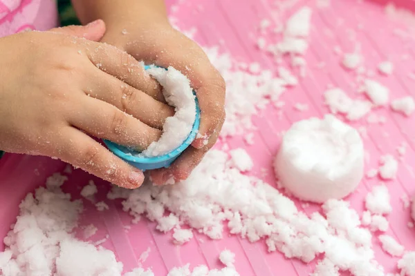 Çocuk ev dekorasyonu için yapay karla oynuyor.