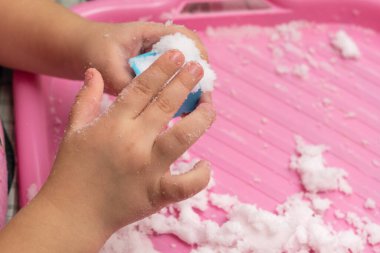 Çocuk ev dekorasyonu için yapay karla oynuyor.