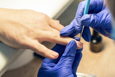 Manikürcü bir manikürcüde manikür yapıyor, tırnaklarına oje sürüyor..