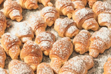 Ev yapımı kekler, fırında pişmiş taze bir tepside süzme peynirli çörekler üzerine pudra şekeri serpiştirilmiş..