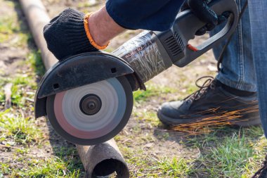 İşçi bir açı öğütücüyle metali keser.