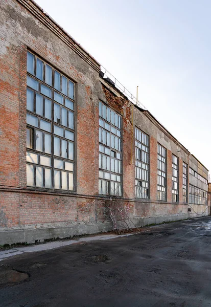 Old crumbling factory building, wall collapse danger.